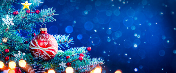 Close-up Of Ornaments On Christmas Tree With Blue Snowy Background - Christmas