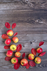 Autumn background. Autumn flat lay: ripe apples, cinnamon sticks and fallen leaves on a wooden background. Top view. Copy space.  