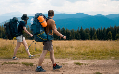 Two people are hiking with backpacks in the mountains.