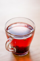 Red berry tea in a transparent cup on the background of a wooden table in a cafe
