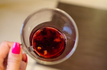 Red berry tea in a transparent cup on the background of a wooden table in a cafe