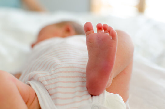 Newborn foot closeup with baby in background