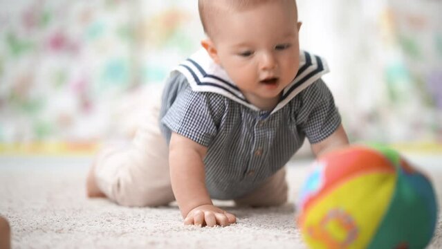 Happy healthy six-month-old baby trying to crawl for the first time on the floor in the nursery. Healthy growth and development of the child's skills