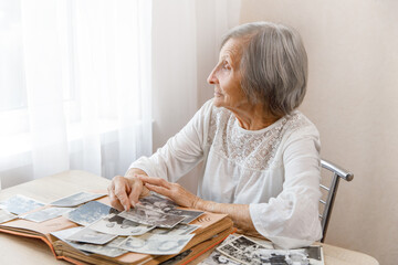 Mature woman watching black and white old photo album at home.Person looking at her own photo was...