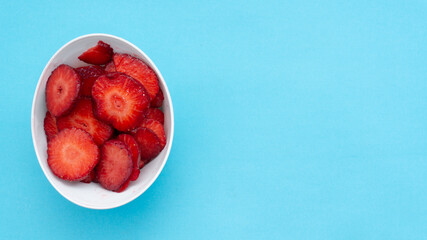 top view of bould of strawberries on turquoise background