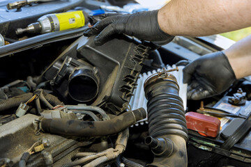 Automobile master hand is holding replacement car air filter as it installed into the engine of vehicle at service center.