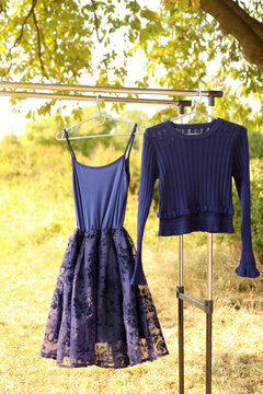 A Blue Dress And A Sweater Are Hanging On A Hanger.