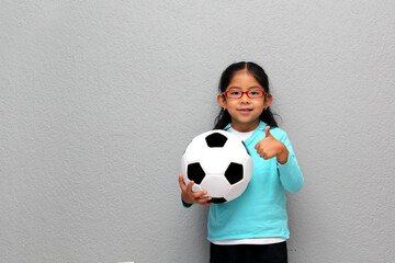 Poor Latino 4-year-old gril plays with a soccer ball very excited that he is going to see the World...