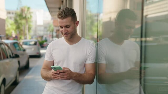 Young caucasian man smiling confident using smartphone at street
