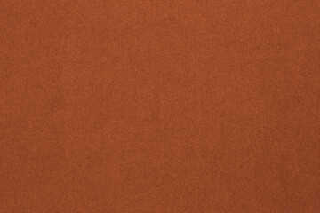 Bright brown colored paper texture. Dark orange tinted background or wallpaper. Textured surface, fibers and irregularities are visible. Top-down