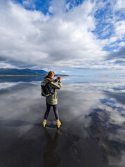 Woman stays on the water surface with the sky reflection. Iceland landscape