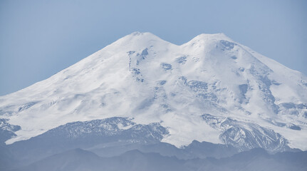 Fototapeta na wymiar Mount Elbrus in the approximation is distinguished by two peaks with rocks, snow and glaciers panoramic view with a clear sky, a warm autumn day