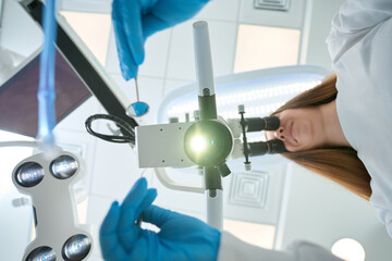 Experienced stomatologist examining patient using modern diagnostic equipment
