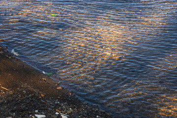 The water of a mountain river. The glittering glass water of a mountain river, shimmering in the summer sun. The texture of a water mountain river. Light beige iridescent color of pure water.