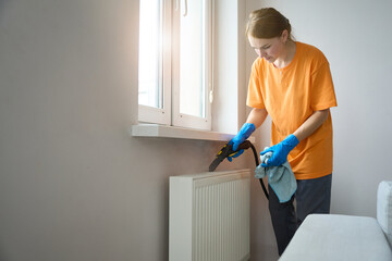Woman from the cleaning company cleaning heaters