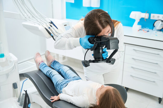 Dentist taking photos of little patient teeth during consultation