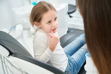 Pre-teen girl complaining of toothache to doctor