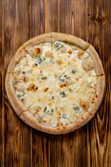 Pizza with four cheeses, mozzarella, blue cheese, Parmesan cheese. Italian cuisine. On a wooden background. View from above.