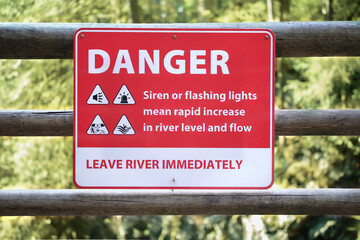 Danger sign about fast rising water on hiking trail bellow a dam. Signage with safety instruction...