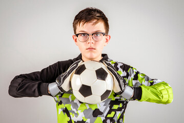 Male youth soccer player wearing goalie gloves and holding a soccer ball