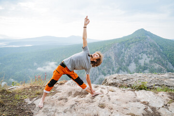 Utthita Trikonasana pose of an elongated triangle, a guy practices yoga standing on top of a mountain, body warm-up, asana triangle, zen meditation in nature