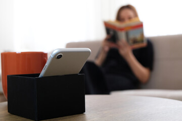 Digital detox concept photo. Woman rejecting social media addiction reading book. Selective focus
