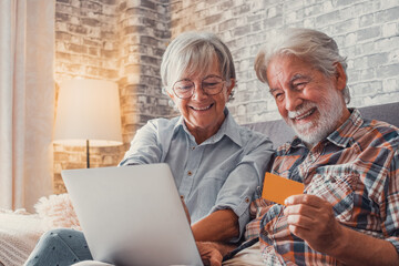 Portrait of couple of cute two happy and excited seniors buying and spending money shopping online...