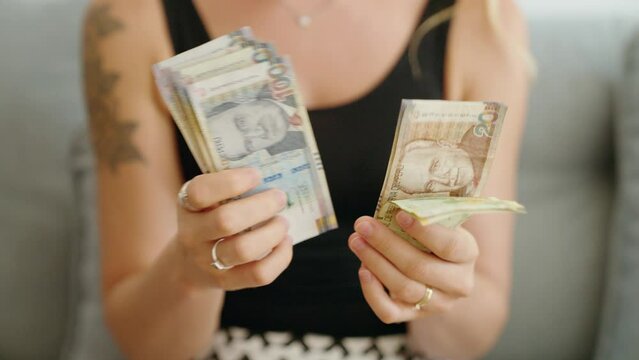 Young woman counting peru sol banknotes at home