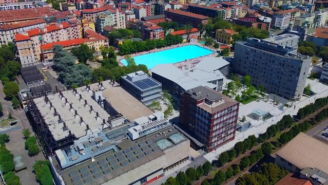 Aerial view of the cityscape and Milano Sport - Centro Balneare Romano swimming pool with clear water. Polytechnic University buildings. Campus and library. Milan Italy 10.2022