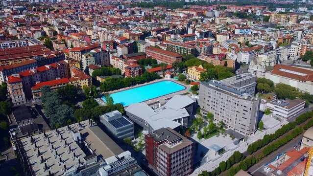 Aerial view of the cityscape and Milano Sport - Centro Balneare Romano swimming pool with clear water. Polytechnic University buildings. Campus and library. Milan Italy 10.2022