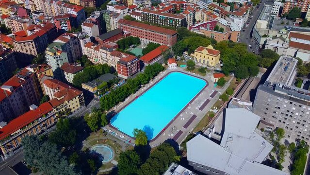 Aerial view of the cityscape and Milano Sport - Centro Balneare Romano swimming pool with clear water. Polytechnic University buildings. Campus and library. Milan Italy 10.2022