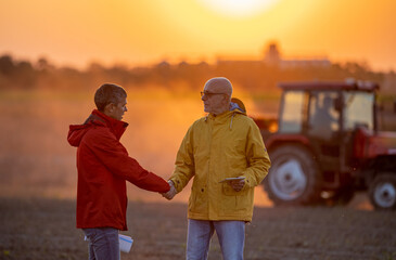Fototapeta premium Farmers shaking hands in field in autumn