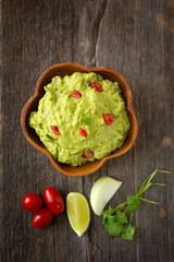 Fresh guacamole with ingredient on a wooden background