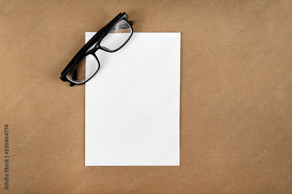 Poster A notebook with glasses in a minimal style top view isolated on brown background of recycled craft vintage paper