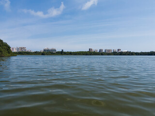 View of the Marapendi lagoon with buildings in the background and surrounding vegetation and trees. Hills in the background. Located near Praia da Reserva in Rio de Janeiro