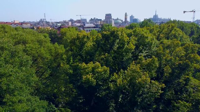 Aerial view of autumn trees in Giardini Indro Montanelli park and the skyline with new skyscrapers. View of modern business offices. Ecology. Clouds over the city. Green Planet. Milan. Italy, 
