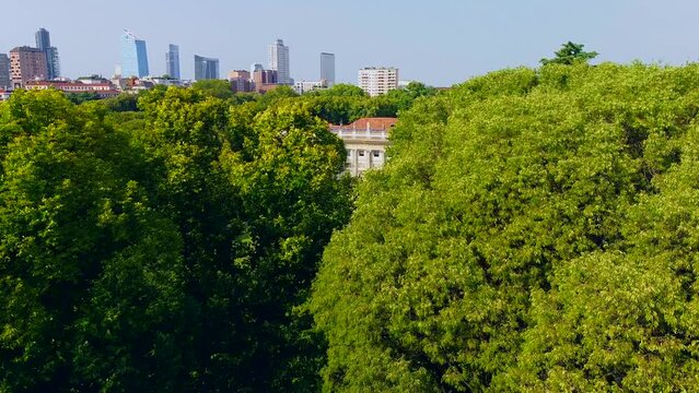 Aerial view of summer trees in Giardini Indro Montanelli park and skyline with new skyscrapers. View of modern business offices. Business. Tourism. Ecology. Clouds over the city. Green Planet. Milan. 