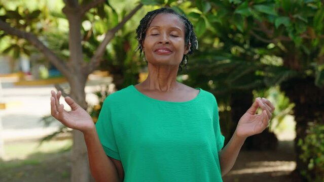 Middle age african american woman smiling confident doing yoga exercise at park