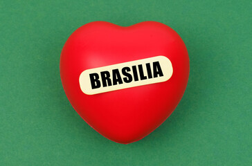 On a green surface lies a red heart with the inscription - Brasilia