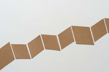 brown paper shapes arranged in accordion or chevron or zig zag form across a blank paper background