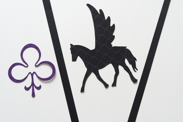 glyph or dingbat of pegasus (winged horse) cutout, black paper stripes, and trefoil decorative shape