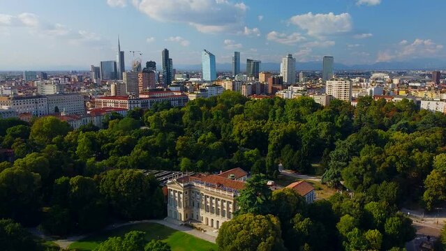 Aerial view of summer trees in Giardini Indro Montanelli park and skyline with new skyscrapers. View of modern business offices. Business. Tourism. Ecology. Clouds over the city. Green Planet. Milan. 