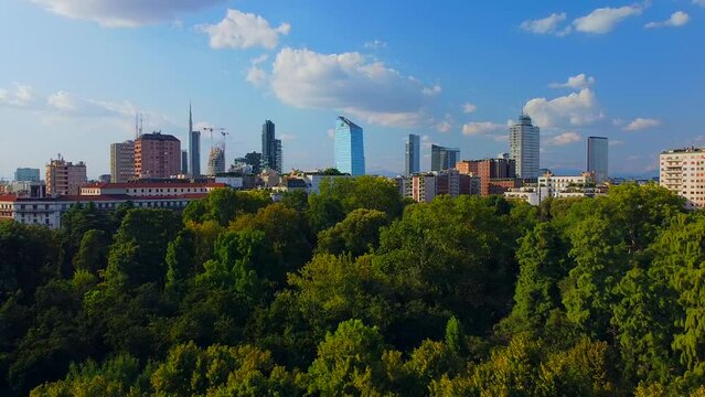 Aerial view of autumn trees in Giardini Indro Montanelli park and the skyline with new skyscrapers. View of modern business offices. Ecology. Clouds over the city. Green Planet. Milan. Italy, 