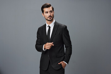 Man confident businessman in a stylish suit with jacket tie and white shirt on a gray background...