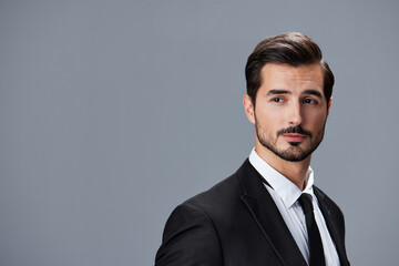 Portrait of a business man in a stylish suit with tie beautiful face on a gray isolated background. Business concept young businessman startup copy space