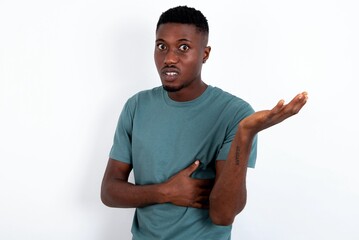 Studio shot of frustrated young handsome man wearing green T-shirt over white background gesturing...