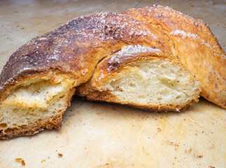 Wicker bun with cinnamon and sugar. Broken wicker bun. Bread product of an unusual shape. Homemade baking. Buns with a ruddy crust.   Pulp baking.