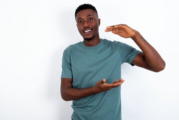 young handsome man wearing green T-shirt over white background gesturing with hands showing big and...