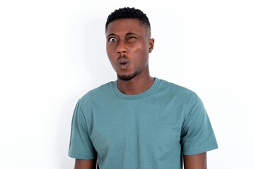 Fototapeta premium young handsome man wearing green T-shirt over white background expressing disgust, unwillingness, disregard having tensive look frowning face, looking indignant with something.