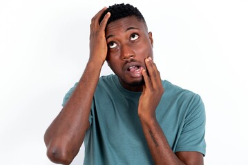 Young gloomy young handsome man wearing green T-shirt over white background , hiding face with...